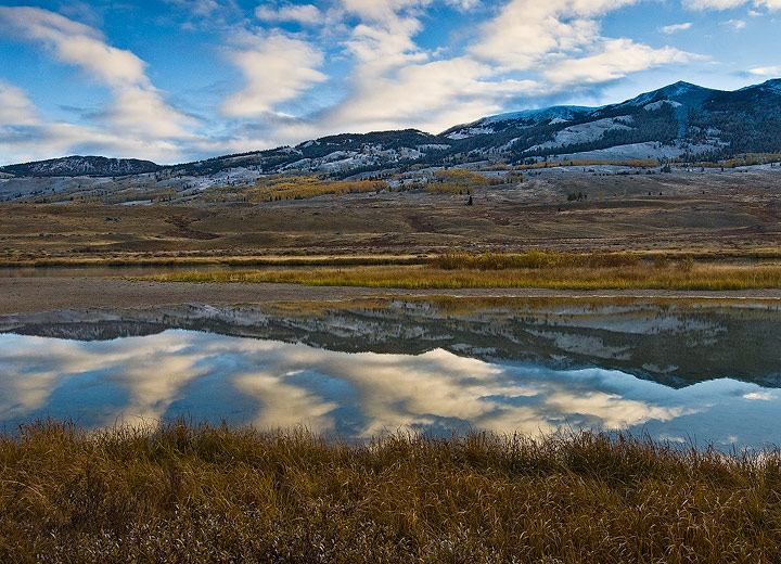 Freshly snow covered peaks of the Wind River Range reflect in the upper Green River on a  Autumn morning