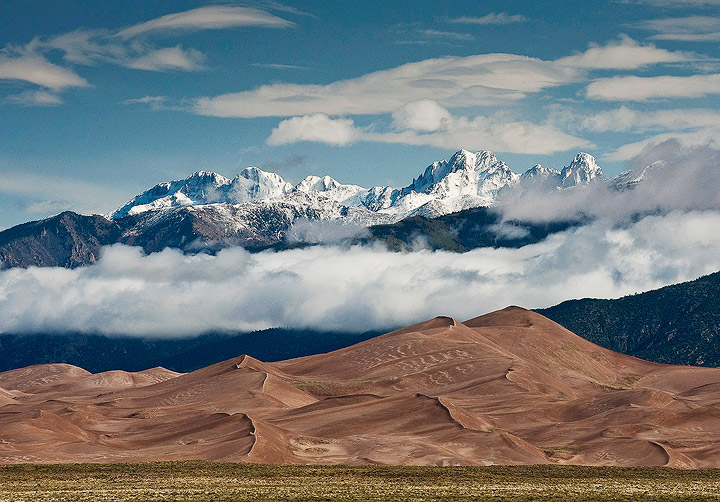 Fresh snow from am early June storm blankets&nbsp; the Crestone Peaks rising over the dunes in Great Sand Dunes National Park...