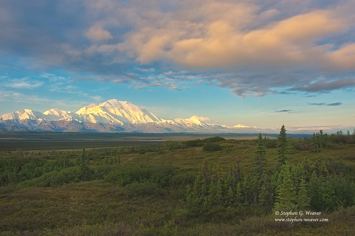 Early morning light illuminates Denali and clouds in the sky