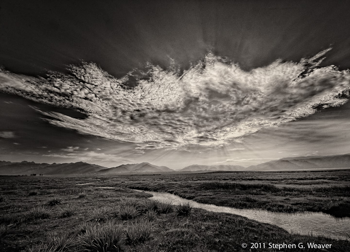 A large backlit cloud looms over the meadows of the Medano Ranch, San Luis Valley, Colorado