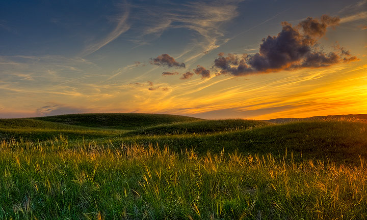 Sunset light illuminates the rolling grass covered hills in The Sand Hills region of Nebraska